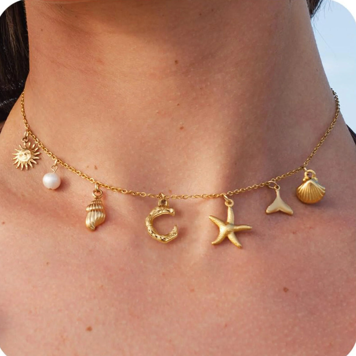 Gold necklace with various charms on a person's neck