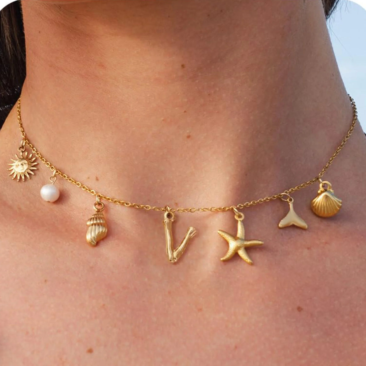 Gold necklace with various charms on a person's neck