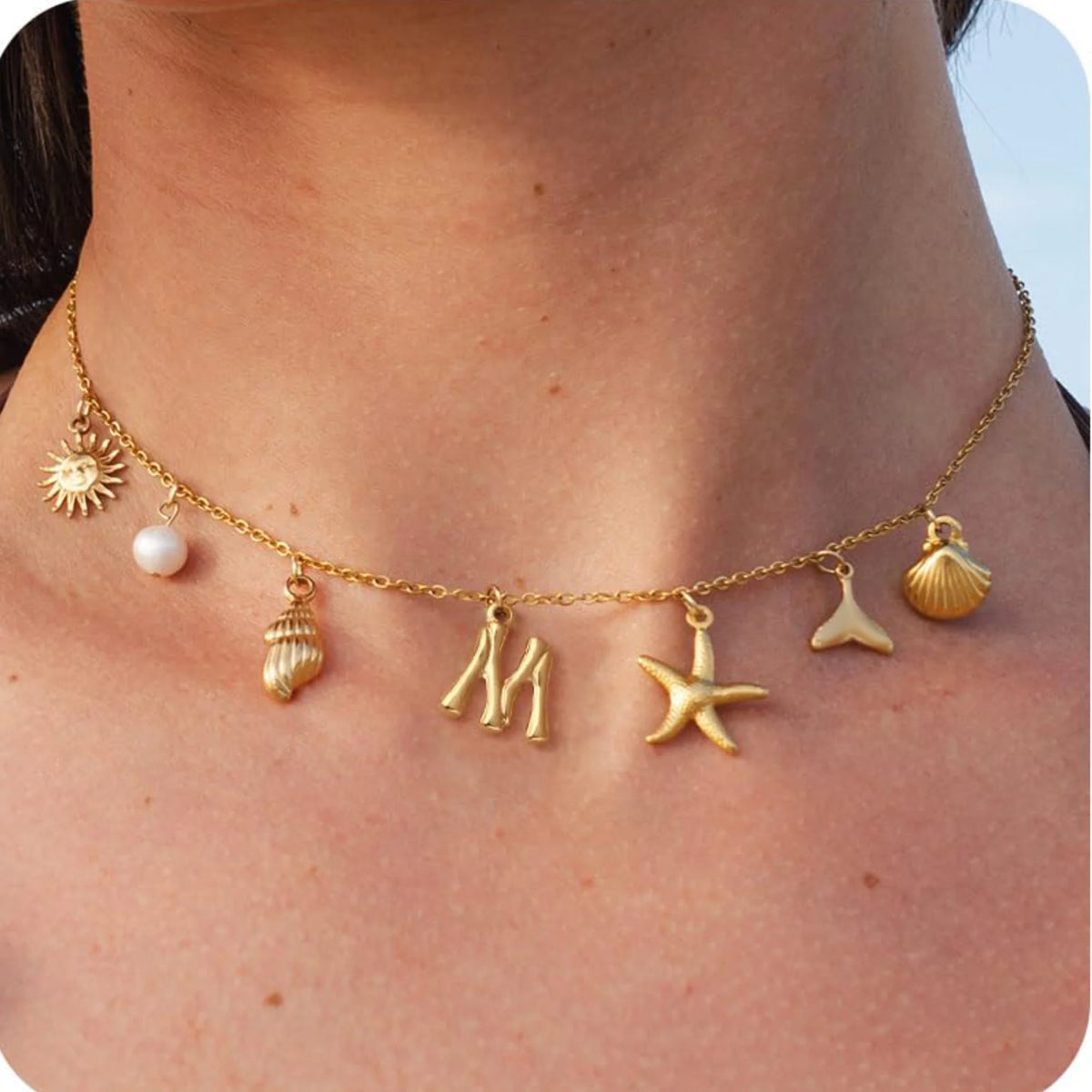 Gold necklace with various charms worn by a person